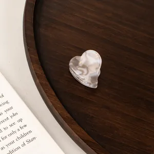 Macro shot of mini heart hair claw clip with white marble texture on wooden tray