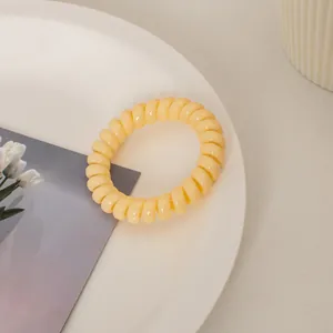 Nahaufnahme des cremiegelben Spiralgummis auf weißem Keramikteller mit Tulpenkarte