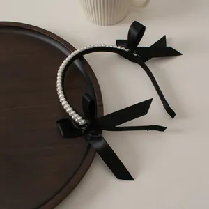Detail view of elegant double-row pearl headband with black satin bow and long ribbons