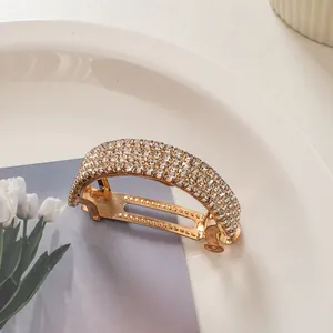 Close-up of curved gold hair clip with three rows of sparkling crystal rhinestones