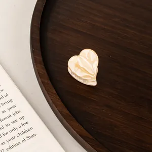 Macro view of mini heart-shaped acetate hair claw clip on vintage wooden background