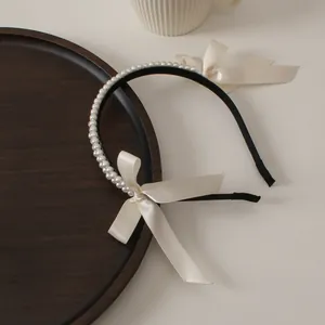 Detail of double-row pearl headband featuring ivory satin bows and long flowing ribbons