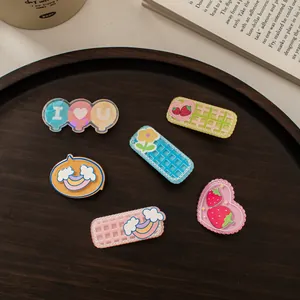 Süße Acryl-Haarclips mit Blumen und Erdbeeren und Glitzereffekt auf einem Holztablett