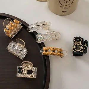 Close-up of bear-shaped hair clips in champagne and iridescent colors on a wooden tray