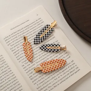 Checkboard patterned acetate hair clips in black and orange on a vintage book