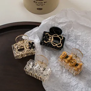 Detail of bear-shaped hair claws in champagne and black colors on a wooden tray