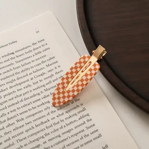 Macro detail of checkered acetate hair clip with golden metal clip on vintage book