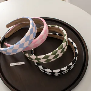 Detail of four colorful checkerboard sponge headbands stacked on a wooden tray
