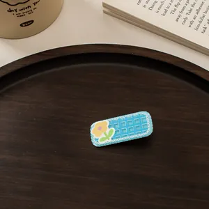 Detailaufnahme der blauen Karo-Haarspange mit Blume auf einem Holztablett