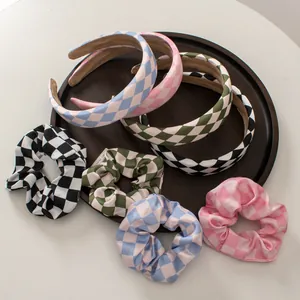 Detail showing various checkered headbands and silk scrunchies on a wooden plate