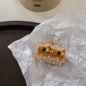 Close-up of cute champagne bear hair claw clip with plush texture and black bow detail