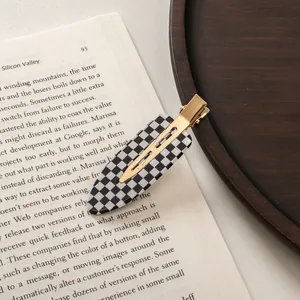 Close-up of checkered acetate hair clip with gold metal clasp on vintage book