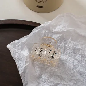 Close-up of champagne bear hair claw clip made of clear acrylic on a rustic wood tray