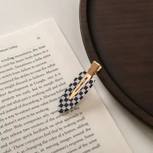 Detail of checkered acetate hair clip with gold metal base placed on an open vintage book