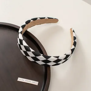 Detail of checkered fabric headband with non-slip brown suede lining on a wooden tray