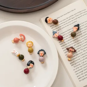 Detailed view of artistic cartoon character hair clips with colorful beads on a gold base