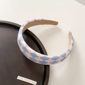 Close-up of wide headband with blue and pink harlequin pattern and beige velvet lining