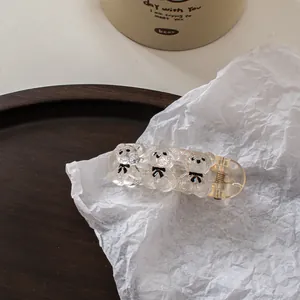 Detailed macro view of three transparent bear hair clips with black bowties and gold spring