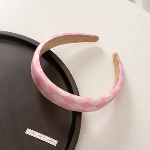 Detail of pink checkerboard wide sponge headband with non-slip lining on wooden tray