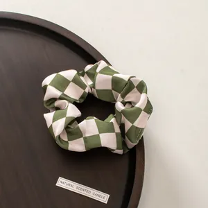 Close-up of olive green and cream checkered scrunchie on a rustic wooden tray