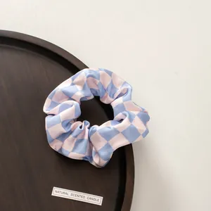 Detail of pink and blue checkered hair scrunchie on a wooden plate in high resolution