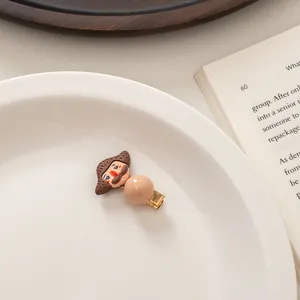 Detail of cartoon character hair clip with bead on white tray with book background
