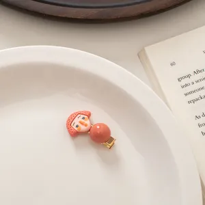 Detailed view of a cute cartoon girl hair clip with a resin bead on a ceramic plate