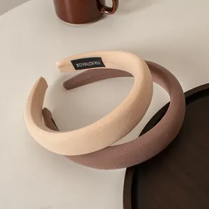 Schicke gepolsterte Schwamm-Stirnbänder in Kaffeetönen auf einem Holztablett