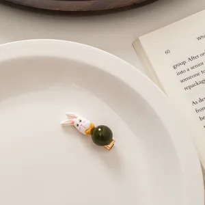 Detail of white rabbit hair clip and dark green bead on a gold metal duckbill hairpin