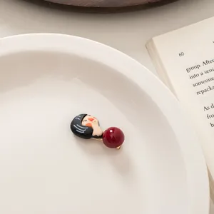 Detail of cute cartoon girl hair clip with red bead on white ceramic plate with book