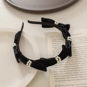 Detalle de diadema de terciopelo negro con anillos de perlas y lazos hechos a mano
