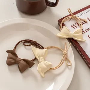 Close-up of matte coffee and cream bow hair ties with braided double-strand elastic bands