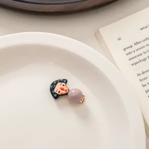 Detailed view of a cute cartoon character hair clip with a lavender bead on a ceramic plate