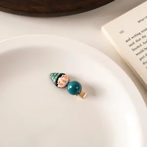 Detailed close-up of a cartoon figure hair clip with green striped hat and a teal bead