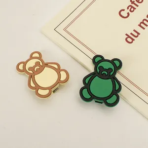 Dettaglio di graziose mollette per capelli a forma di orso opaco color crema e verde
