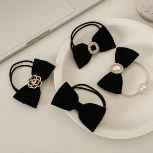 Dettaglio di elastici per capelli in velluto nero con perle, strass e decori floreali