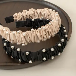Elegant pleated satin headbands with pearls in black and beige, set of two on wooden tray