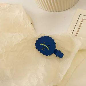Gros plan d'une pince à cheveux ours bleu mat sur papier beige avec éclairage chaleureux