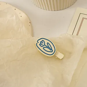 Gros plan d'une pince à cheveux mate crème avec motif tulipe sur fond doux