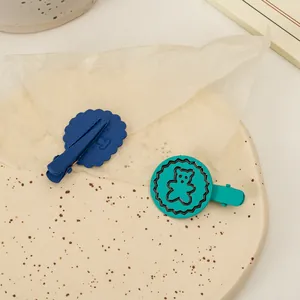 Détail de barrettes ours mates bleu et sarcelle sur un plateau en céramique élégant