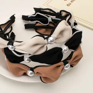 Detail of three twisted fabric headbands with large pearls on a ceramic plate