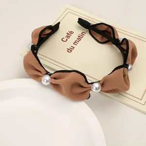 Close-up of brown ruffled fabric headband featuring vintage large white pearls details