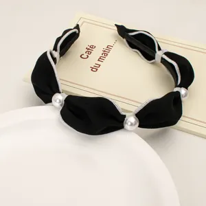 Detail of a vintage French style black fabric headband with pearls and white wavy edges