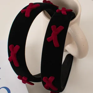 Retro black velvet headband with red flocked bows hanging on a white ceramic mug