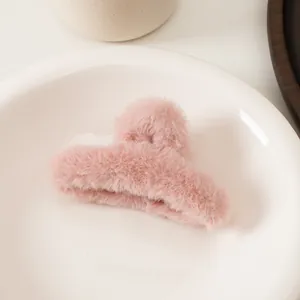 Détail d'une pince à cheveux en fausse fourrure rose douce avec texture moelleuse sur plat