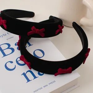 Detail of vintage black velvet headband featuring five red velvet bows in a soft setting