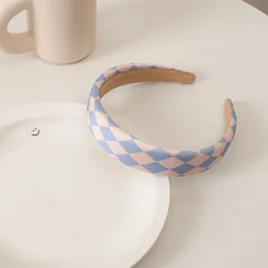 Close-up of thick wide-brimmed sponge headband with pink and blue checkered fabric pattern