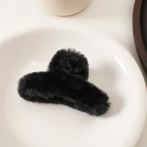 Gros plan sur une pince à cheveux en peluche noire douce sur un plateau pour coiffure
