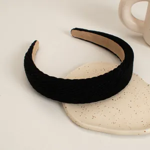 Detail shot of the black corduroy fabric texture and plush lining on the wide headband