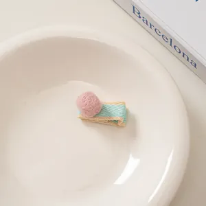 Detail der Haarspange aus rosa Wollfilz mit buntem Webband um die Schnabelklammer herum